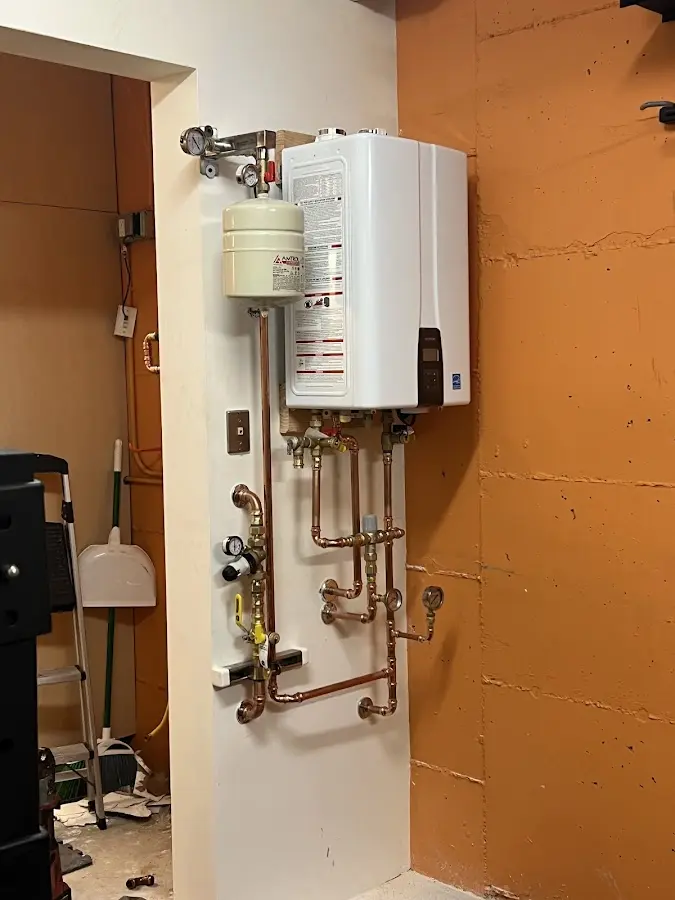 Plumbing technician inspecting water heater connections in Hutchinson